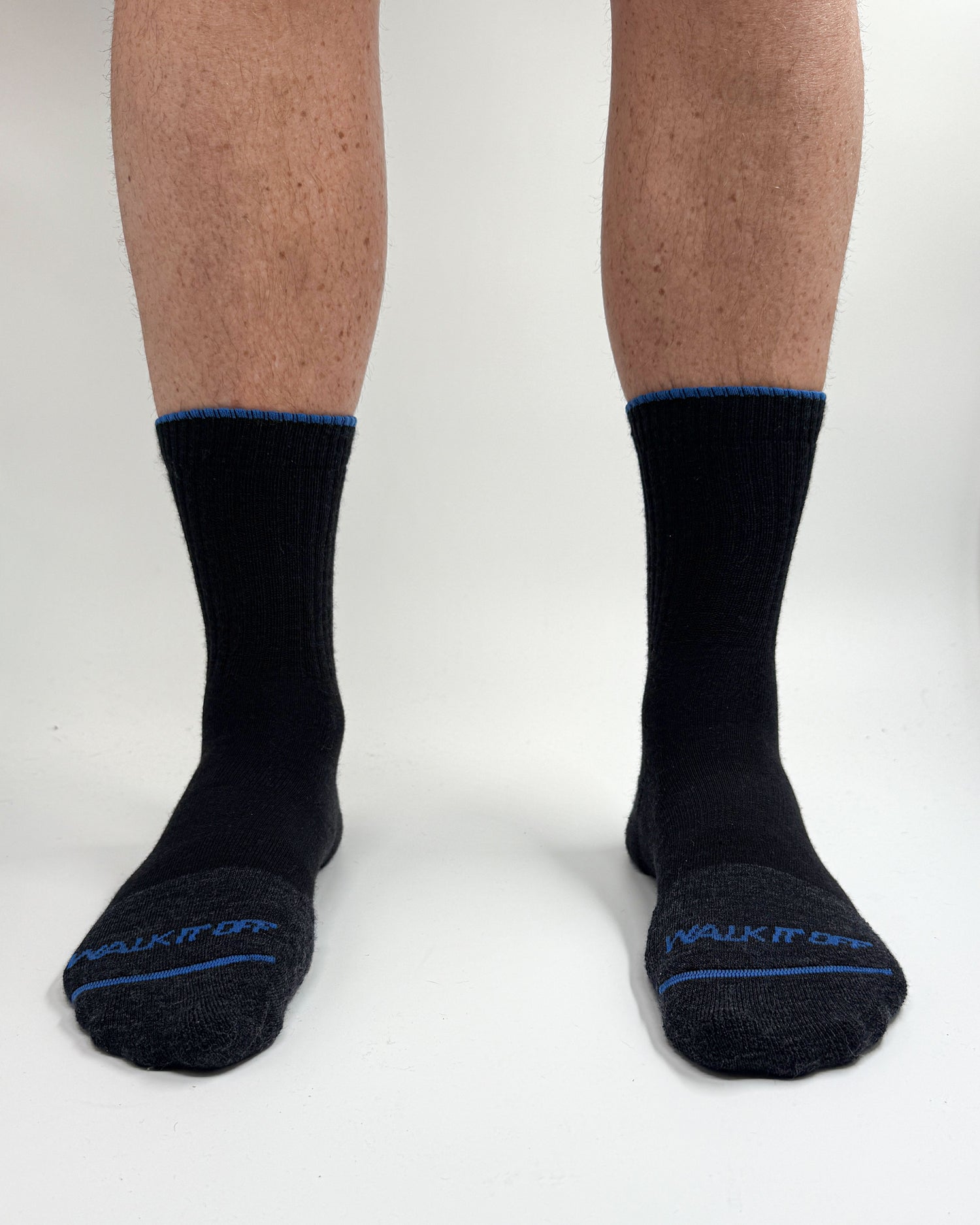 Model draagt de WALK IT OFF merino sokken in de kleur Black Magic, gefotografeerd recht van voren op een witte achtergrond.