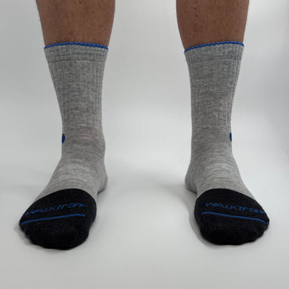 Model draagt de WALK IT OFF merino sokken in de kleur Platino, gefotografeerd recht van voren op een witte achtergrond.