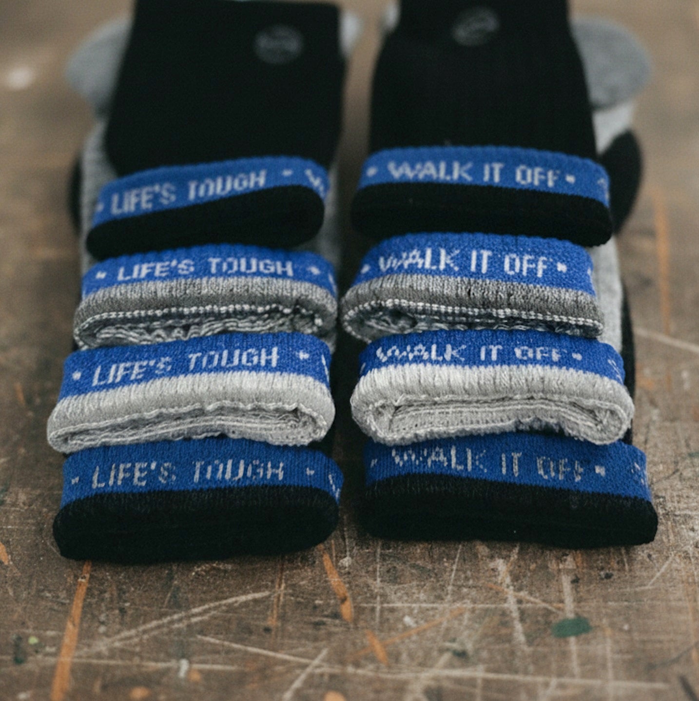 Close-up van gestapelde WALK IT OFF merino sokken met blauwe ‘Life’s Tough – Walk It Off’ branding.