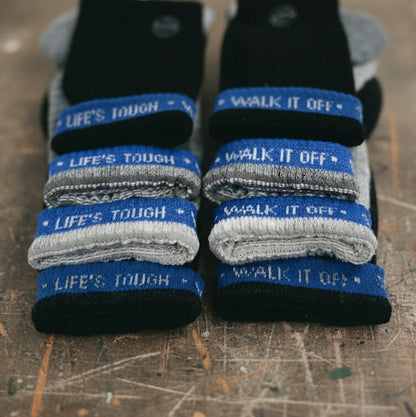 Close-up van gestapelde WALK IT OFF merino sokken met blauwe ‘Life’s Tough – Walk It Off’ branding.